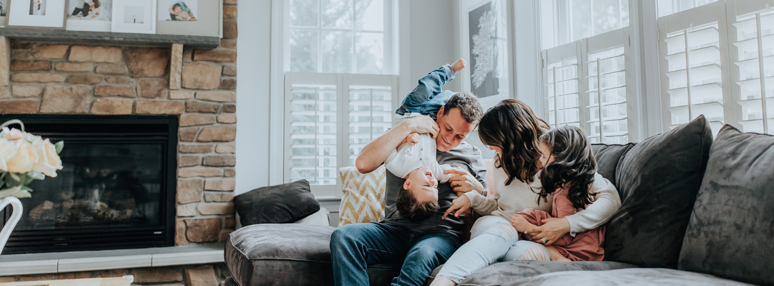 A family relaxing and laughing together in a bright Ontario home, sitting on a cozy living room couch near a fireplace. Ideal visual for Westland Insurance Ontario home insurance coverage.