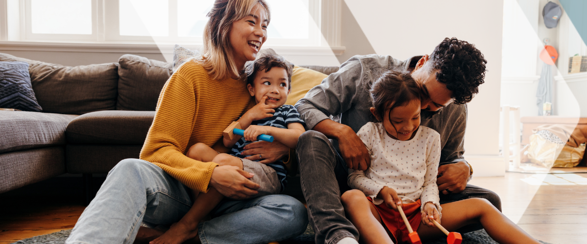 Young parents saving for retirement with a young family, sitting on the living room floor and playing with their two kids